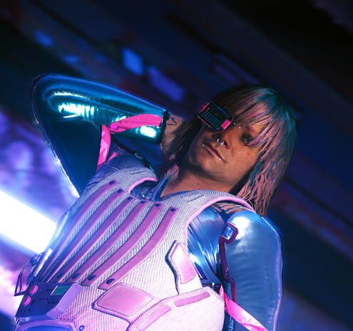 a non-canon v posing in lizzie's bar with a blue netrunner suit on and a pink and white bullet-proof vest